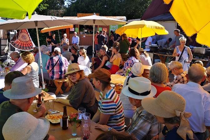 Foto des Eröffnungsfestes mit vielen Leuten an Festbänken